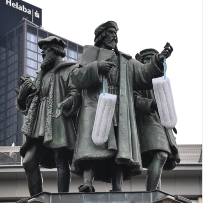 Die Gutenberg Statue in Frankfurt hat zwei große Tampons von den Armen hängen.