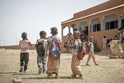Kinder laufen über einen Schulhof