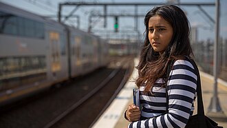 Mädchen an einem Bahnsteig, das schaut, als würde sie sich nicht sicher fühlen