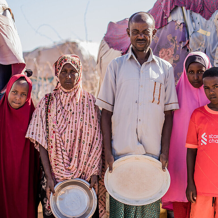 Eine Familie steht vor zwei Zelten. 
