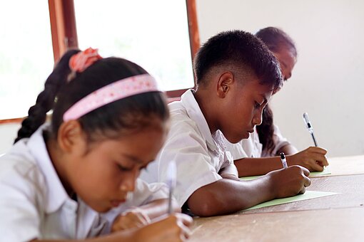 Mädchen und Junge beim Schreiben in der Schule.