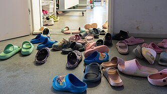 Vor einem Raum mit offener Tür stehen jede Menge Hausschlappen