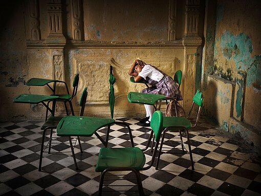 Mädchen in marodem Schulraum sitzend