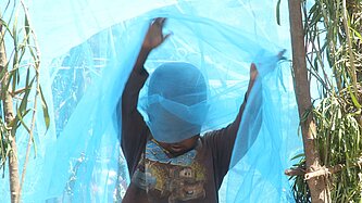 Junge in Ruanda spielt mit Moskitonetz