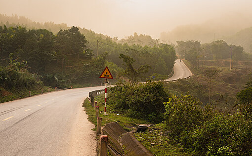 Im Morgennebel liegt eine einsame Landstraße in Vietnam.