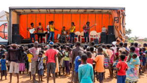 Aufklärung und Unterhaltung durch mobiles Bühnenprogramm in Malawi Kinder und Familien verfolgen ein mobiles Theaterstück oder eine Musikvorführung in Malawi