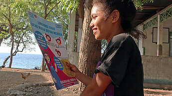 ein 14-jähriges Mädchen aus Indonesien hält ein Infopapier in der Hand und liest darin