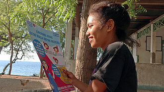 ein 14-jähriges Mädchen aus Indonesien hält ein Infopapier in der Hand und liest darin