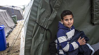 ein kleines Kind sitzt vor einem Zelt