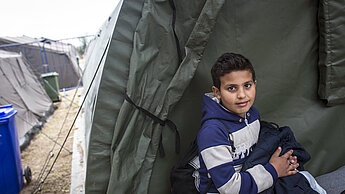 ein kleines Kind sitzt vor einem Zelt