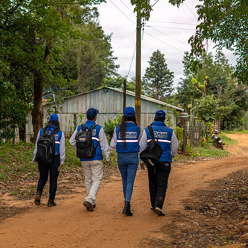Mehrere Mitarbeitende von Plan International gehen durch eine ländliche Gemeinde in Paraguay.