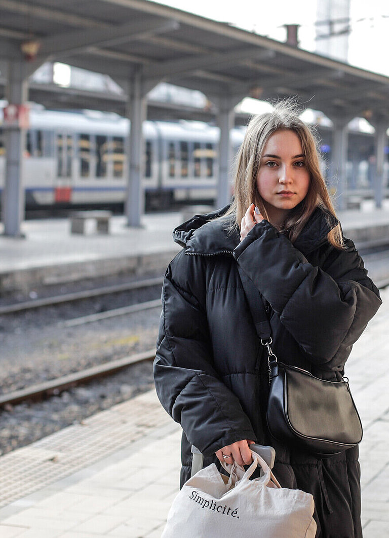 Eine junge Frau steht an einem Bahngleis
