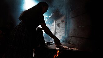 Eine Frau steht am Herd und backt Tortillas.