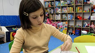 Ein junges Mädchen malt ein Bild mit Wasserfarben