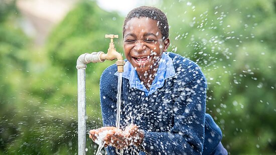 Bild: Ein Mädchen hält die Hände unter einen Wasserhahn