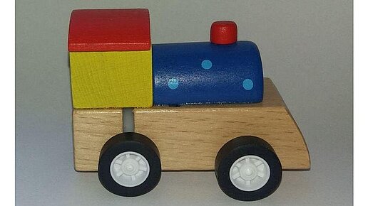 Kleine bunte Holzlokomotive im Bausteinelook mit Rädern. 