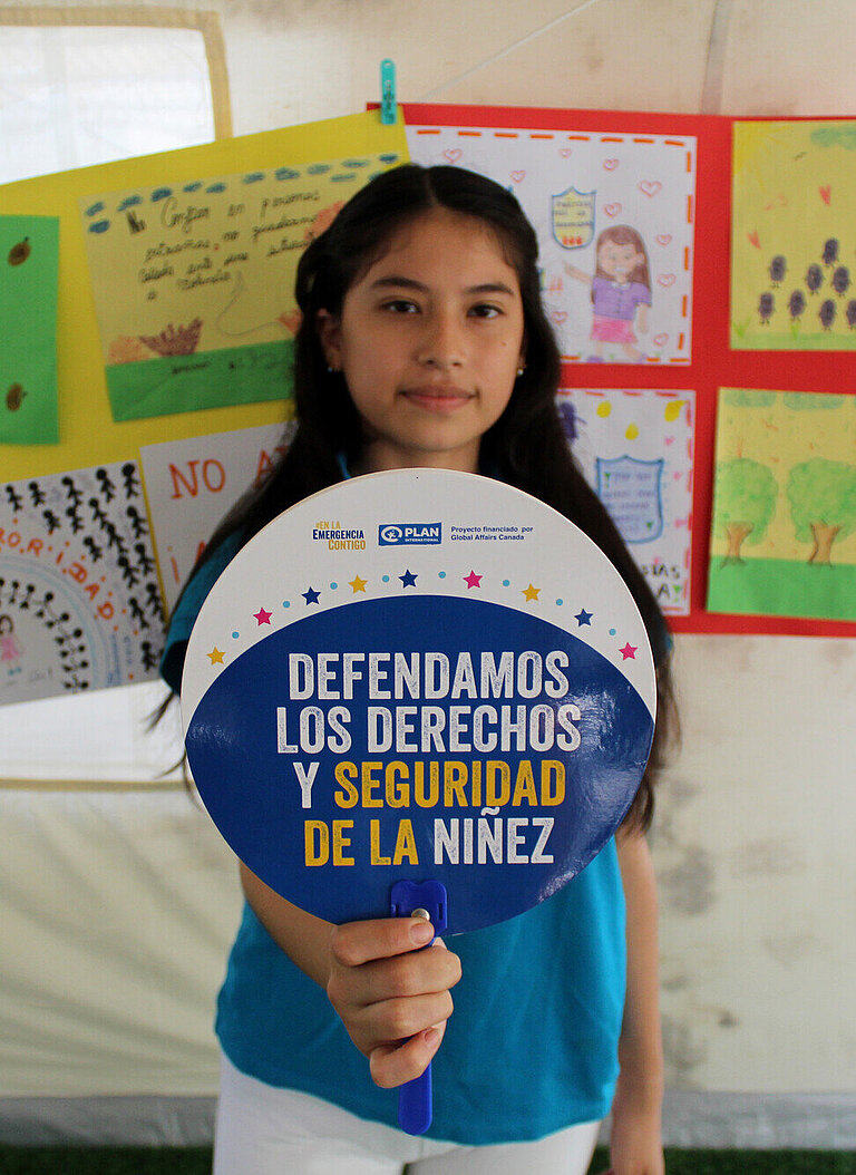 Ein Mädchen hält ein Schild hoch, auf dem etwas in Spanisch steht