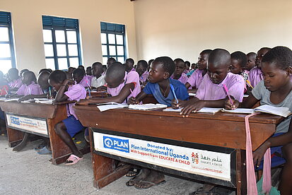 Heranwachsende schreiben an von Plan bereitgestellten Schulbänken