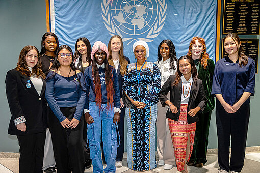 Jugenddelegierte der Plan International Delegation stehen vor der UN-Flagge beim UN-Hauptquartier in New York während der 69. Sitzung der Frauenrechtskommission (CSW69). Sie setzen sich für die Stimmen und Rechte von Mädchen und jungen Frauen ein.