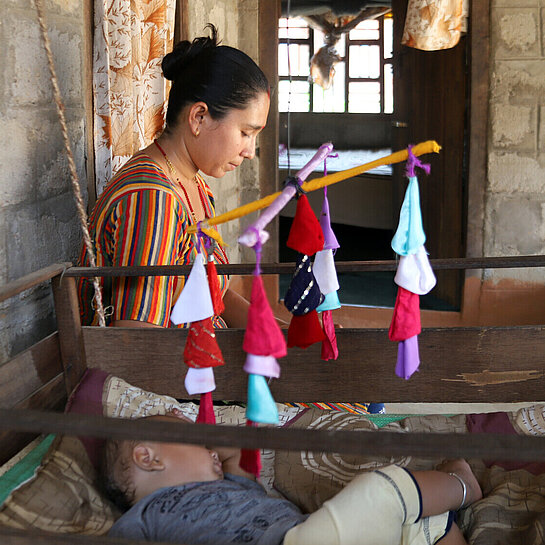 Ein buntes Mobile, das Kunta gebastelt hat, hängt über dem Kinderbett