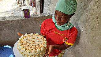 Eine junge Frau hält eine fertige Torte in der Hand, die mit Sahne verziert ist
