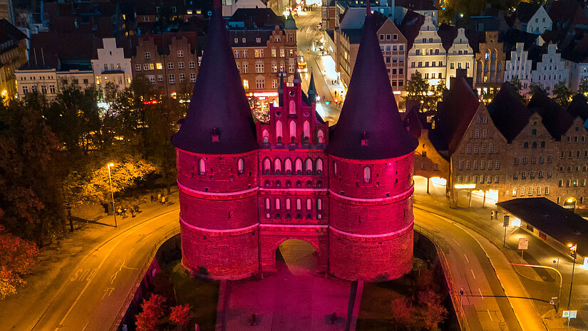 Auch in diesem Jahr leuchteten in ganz Deutschland wieder 60 Gebäude und Wahrzeichen in kräftigem Magenta, darunter das Holstentor in Lübeck. ©Fotograf photography-leisner.de