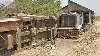 Ausrangierte Lok steht vor einem Lokschuppen.