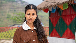 Eine junge Frau aus Nepal erhält durch eine Berufsausbildung im Jugendförderprogramm neues Einkommen und Perspektiven in Nepal. Junge Frau aus Nepal steht vor ihrem Haus in Dhanusha nach erfolgreicher Teilnahme am Jugendförderprogramm.