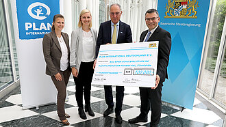 Symbolische Scheckübergabe in Höhe von 100.000€. V.l.n.r. Nicole Schmidt, Referentin Bayern und Baden-Württemberg (Plan), Pia Schmalhaus, Kinderschutzbeauftragte (Plan), Dr. Werner Bauch, Vorstandsvorsitzender (Plan) und Staatsminister Dr. Florian Herrmann. © Bayerische Staatskanzlei