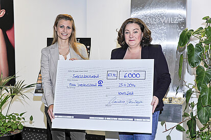 Claudia Steinberger, Geschäftsführerin der MALU WILZ Beauté, übergibt den Spendenscheck an Nicole Haid von Plan.