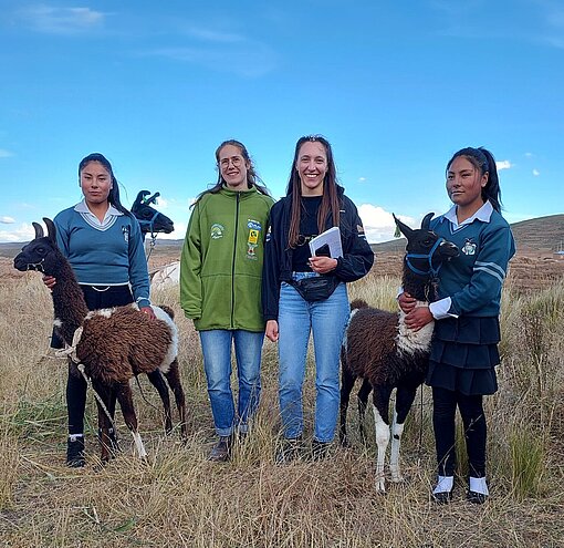Auf dem Bild sind vier Personen, darunter jugendliche Zwillinge. Sie halten zwei Lamas, die auch als Zwillinge zur Welt kamen. 