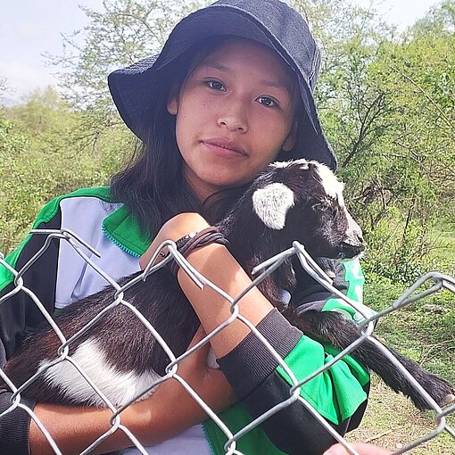 Eine junge Jungendliche hält ein kleines Zicklein im Arm