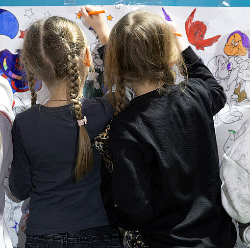 Vier Mädchen stehen an einer Malwand und bemalen diese