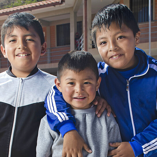 Drei Jungs in Bolivien umarmen sich