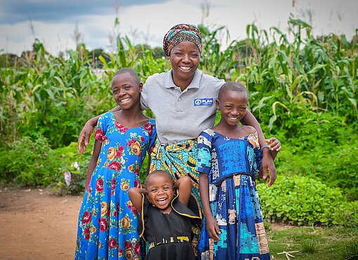 Edwina steht mit drei ihrer Töchter grinsend vor ihrem Maisfeld