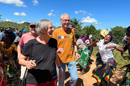 Dorfgemeinschaft begrüßt Gäste mit Tanz auf einem Weg in Malawi.