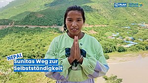 Sunita aus Nepal zeigt ihre Dankbarkeit und steht vor einer grünen Berglandschaft auf dem Weg zur Selbstständigkeit