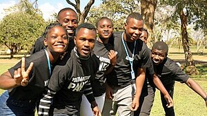 Junge Aktivist:innen in Sambia engagieren sich für Klimaschutz und Gemeinschaft. Gruppe junger Menschen in Sambia posiert fröhlich im Freien bei einem Jugendprojekt für Klimaschutz und soziale Gerechtigkeit.