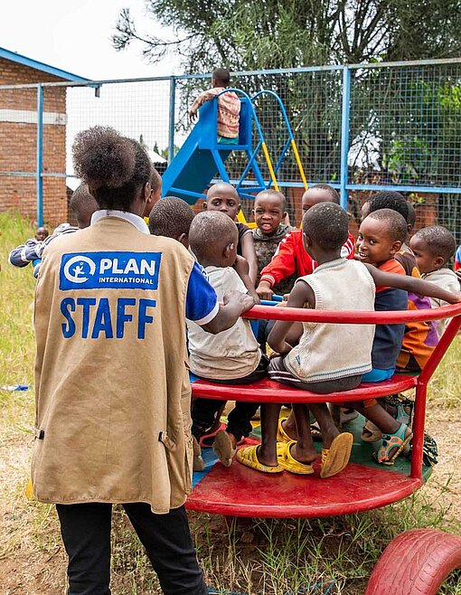 Auf einem Spielplatz behütet eine Frau Kinder auf einem Karussell