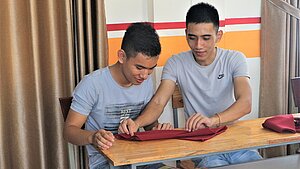 Gastronomie-Kurs: Serviettenfalten im Training Zwei junge Männer falten Servietten im Unterricht eines Gastronomie-Kurses in Vietnam.