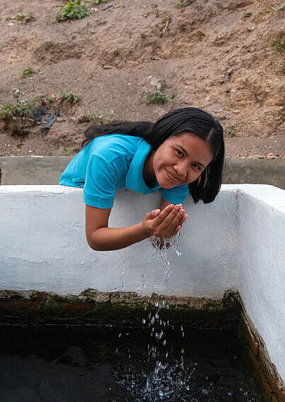 Das Wasser von Pauró – für Lizeth mehr als nur ein Durstlöscher, sondern Teil ihres kulturellen Erbes Mädchen aus Bolivien trinkt von der natürlichen Wasserquelle