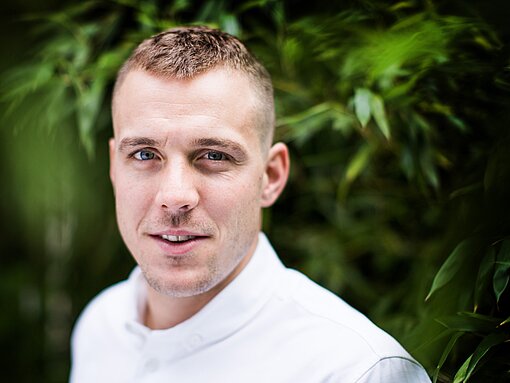 Kentin Mahé Ein junger Mann mit einem weißen Trikot steht vor einer grünen Hecke