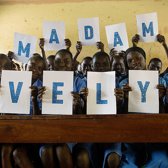 Schulklasse hält Schilder, die „Madam Evelyn“ buchstabieren
