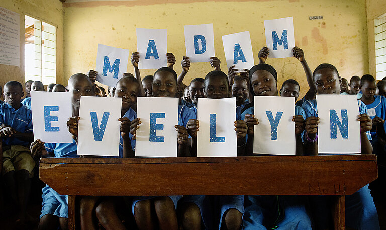 Schulklasse hält Schilder, die „Madam Evelyn“ buchstabieren