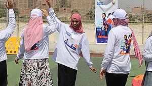 Junge Frauen nehmen in Ägypten an einer Aktion zum Internationalen Frauentag teil und tanzen gemeinsam auf einem Sportplatz, organisiert von Plan International.