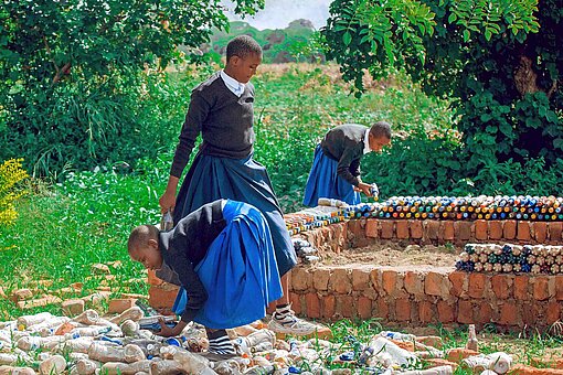 Mädchen in Schuluniformen sortieren leere Plastikflaschen
