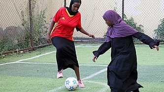 Zwei Mädchen spielen auf einem Fußballplatz