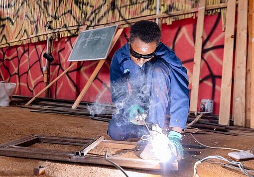 Auszubildende macht Schweißarbeiten auf dem Boden