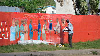 Ebola-Krise 2014: Ein Künstler animiert mit einem Wandbild in der liberischen Hauptstadt Monrovia zum Schutz vor Ansteckung durch Händewaschen. Plan International arbeitete seinerzeit bereits entlang des globalen Risikomanagement-Systems. ©Neil Brandvold