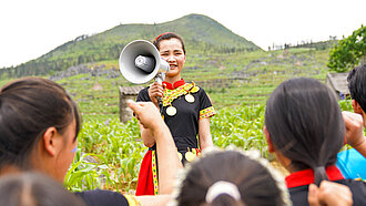 Ein Mädchen steht vor einer Gruppe Kinder und spricht in ein Megaphon.